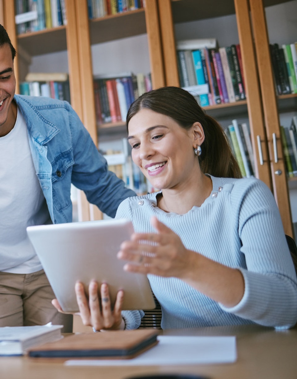 Personas mirando una tablet en una biblioteca