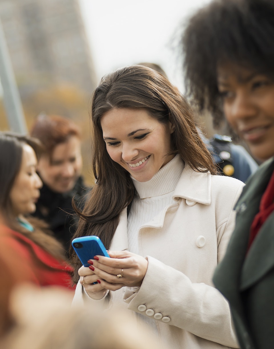 Mujer en medio de una multitud mirando su smartphone
