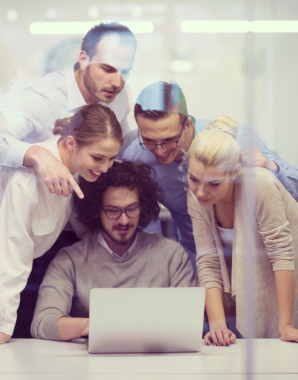 Personas empresarias mirando la pantalla de un portátil en un contexto de oficina.