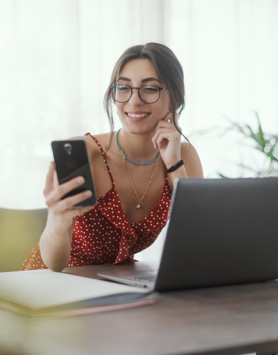 Mujer consulta su smartphone mientras teletrabaja.