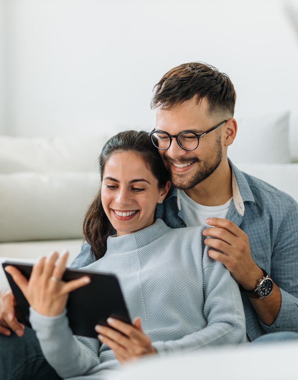 Personas sonriendo mientras miran una tablet.