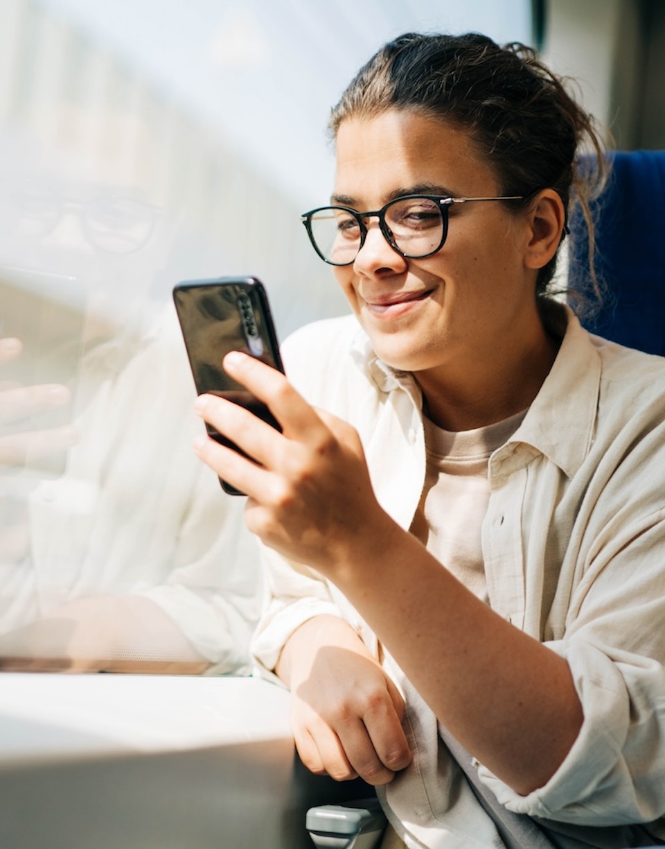 Mujer mirando su teléfono móvil desde un tren.