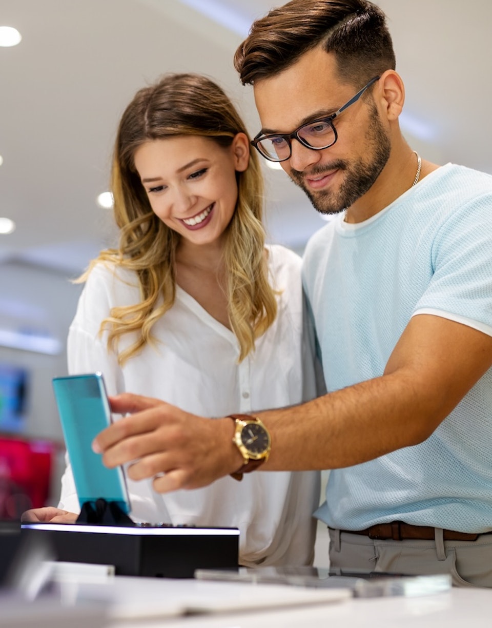 Dos personas mirando un smartphone en una tienda de telecomunicaciones