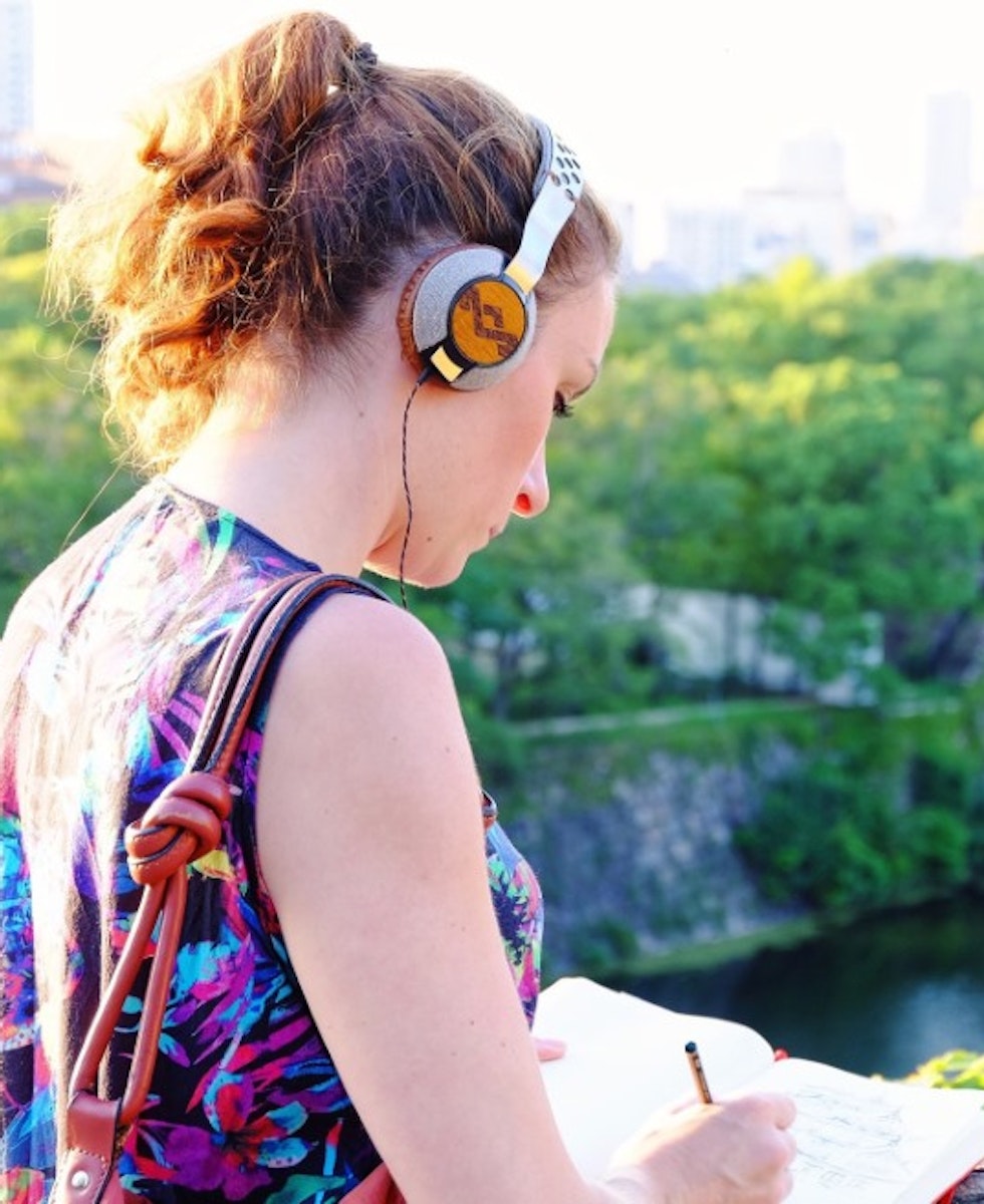 Chica escribiendo en un cuaderno mientras oye música en la ciudad