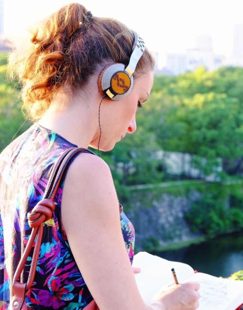 Chica escribiendo en un cuaderno mientras oye música en la ciudad