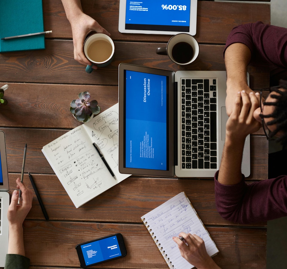 Grupo de personas en un ambiente corporativo trabajando con diferentes dispositivos electrónicos